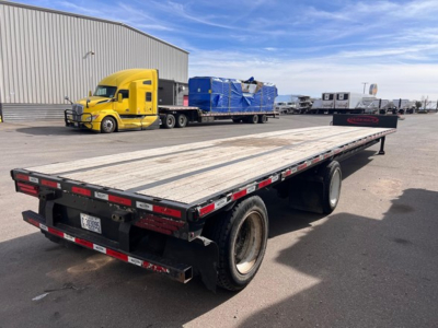Trailer flatbed with wood deck showing rear lights and dual wheels under the long deck.