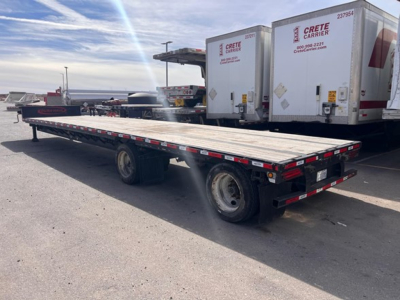 Trailer flatbed drop deck trailer showing long aluminum deck, tandem axles, rear lighting, and reflective tape along sides.