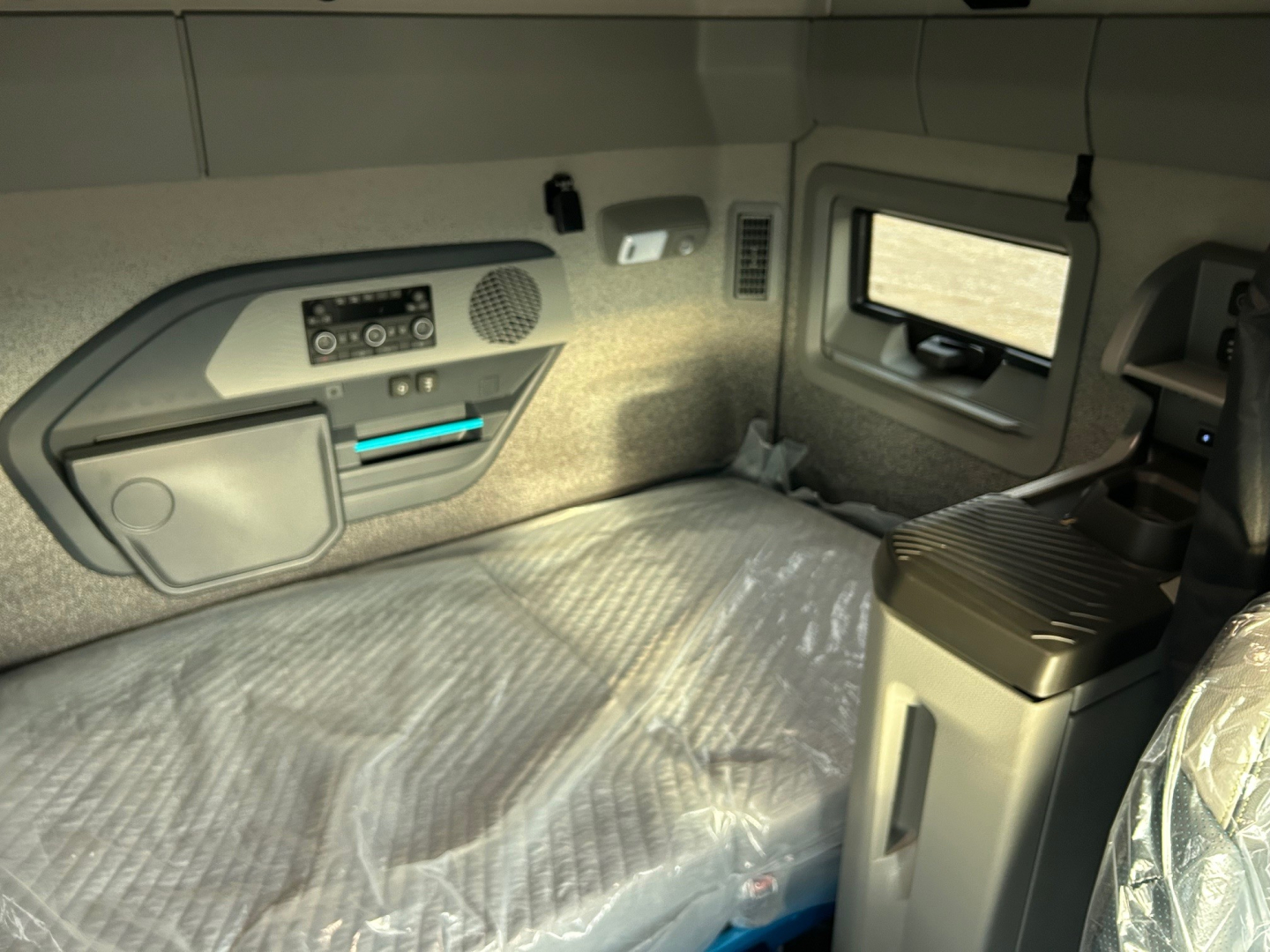 Volvo VNL interior sleeper cab with control panel, storage compartments, window, and seating area visible.