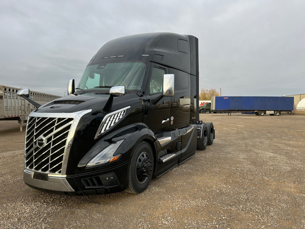 Volvo VNL64T660 semi-truck in black with chrome grille and aerodynamic mirrors, front-left view, daytime outdoor lot.