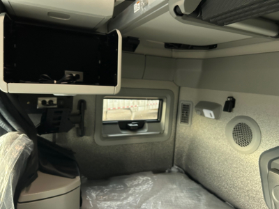 Volvo VNL64T660 cab interior showing overhead monitor mounting area and side storage with window and speaker panel.