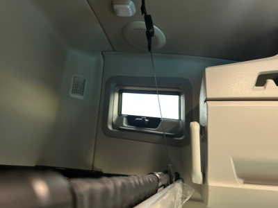 Cab interior of a Volvo VNL truck sleeper showing window, overhead vent, and storage cabinet with a hanging cord.