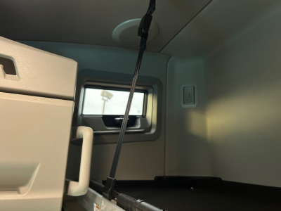 Cab interior of a new Volvo VNL64T660 truck bunk area showing window and storage panel.