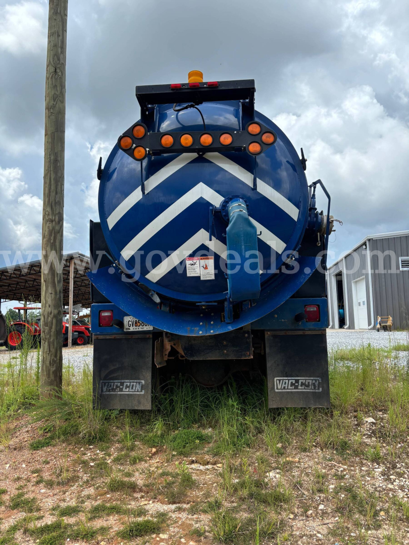 Vacuum truck rear showing blue tank with white chevron markings and orange warning lights.