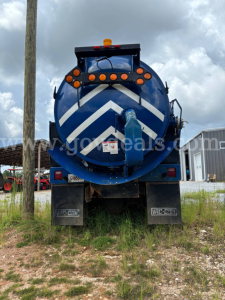 Vacuum truck rear showing blue tank with white chevron markings and orange warning lights.