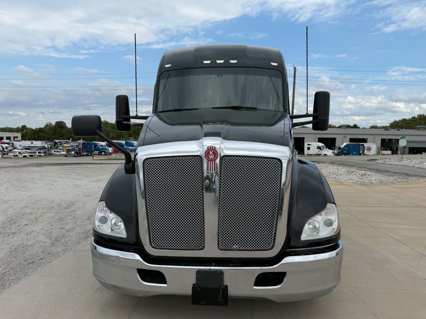 Kenworth T680 front view showing large chrome grille with mesh, Kenworth emblem, dual large mirrors, and gray bumper.