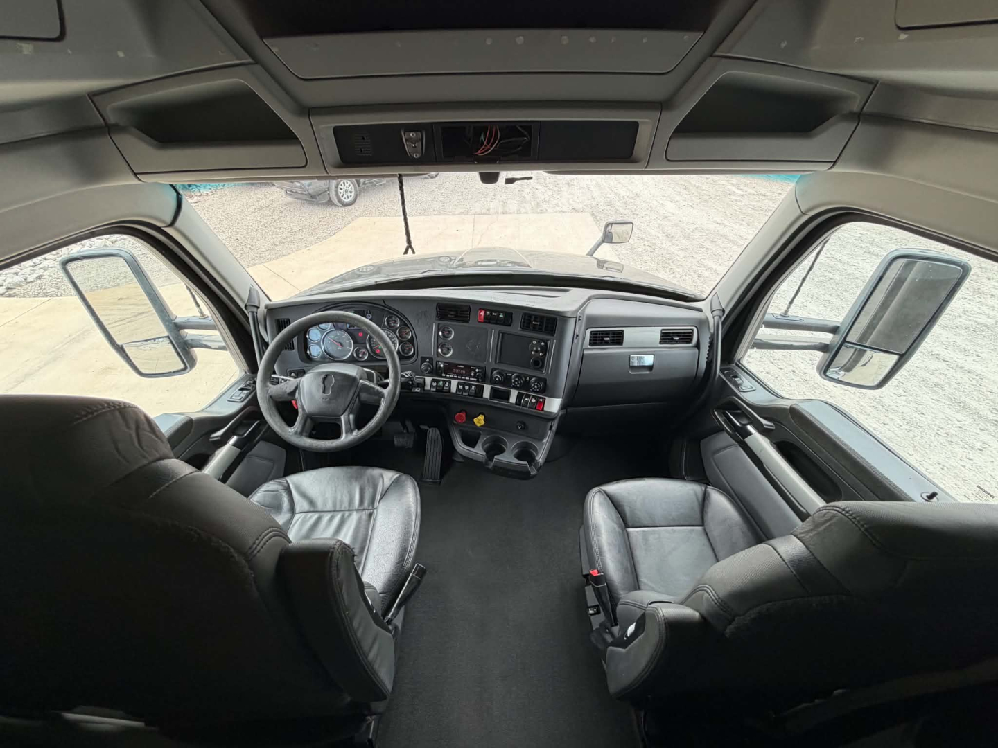 Kenworth T680 truck cab interior showing steering wheel dashboard and seats with digital gauges.