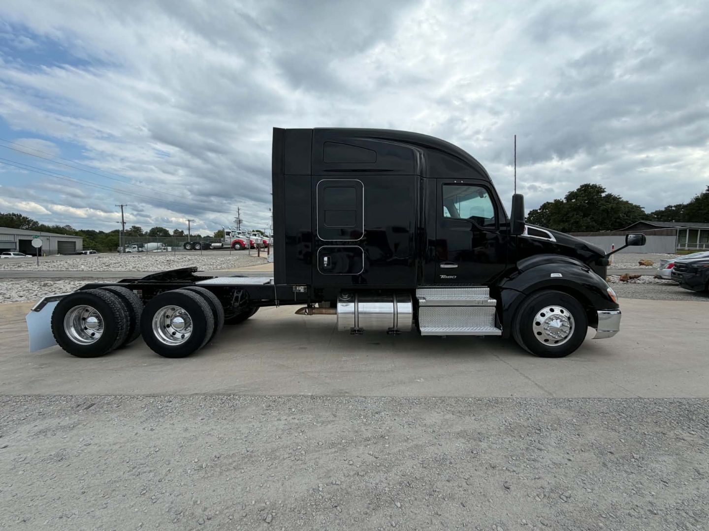 Truck side view of a black 2022 Kenworth T680 conventional sleeper, 6x4 chassis, long cab, dual rear axles, chrome exhaust and fuel tanks, no visible damage.