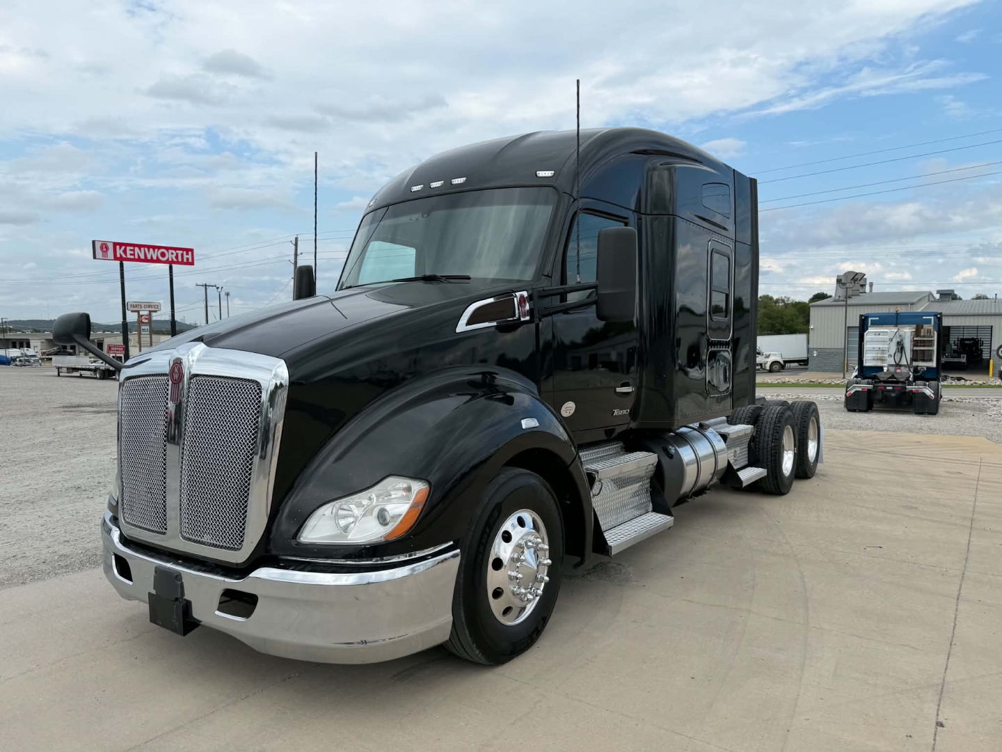 Kenworth T680 in-service black sleeper tractor showing front grille, chrome bumper, large headlights, side fuel tanks, and rear dual wheels.