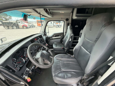Kenworth T680 cab interior showing steering wheel, dashboard gauges, driver seat, and passenger seat.