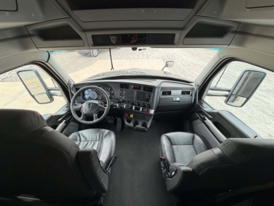 Kenworth T680 truck cab interior showing steering wheel dashboard and seats with digital gauges.