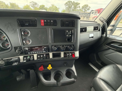 Kenworth T680 cab interior view showing instrument cluster, steering column, center console with controls and cup holders.