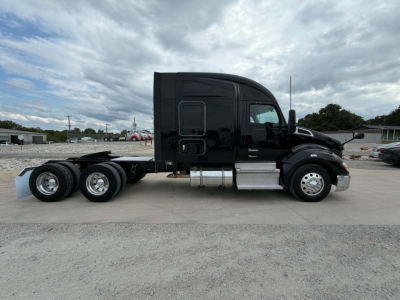 Truck side view of a black 2022 Kenworth T680 conventional sleeper, 6x4 chassis, long cab, dual rear axles, chrome exhaust and fuel tanks, no visible damage.