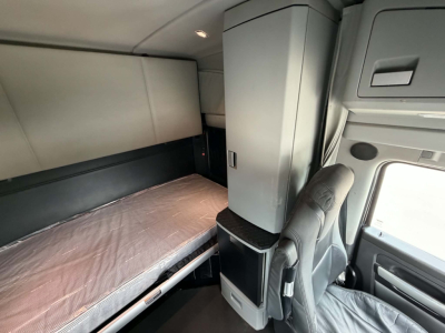 Kenworth T680 sleeper cab interior with bunk bed and storage cabinet visible.