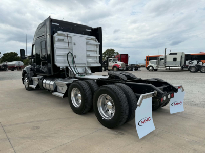 Kenworth T680 tractor rear view showing dual rear axles, mud flaps, and chrome fuel tanks with fifth wheel and sleeper cab.