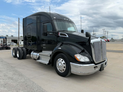 Kenworth T680 tractor cab in black, front three-quarter view showing chrome grille, dual exhaust, fuel tanks, and aerodynamic mirrors.