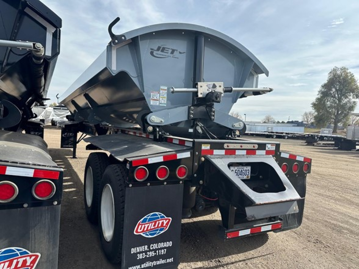 Jet DUMP side dump trailer showing rear view with JET logo, hitch mechanism, and rear bumper with reflective tape and utility sticker.