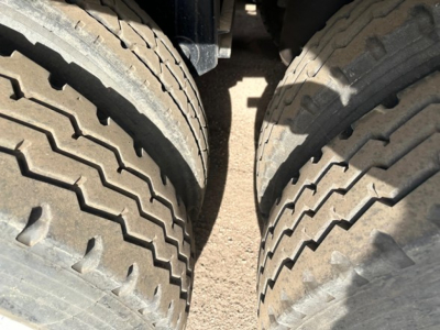Rear view of a Jet Air Ride Side Dump trailer showing dual large tires with deep tread and gravel ground between them.