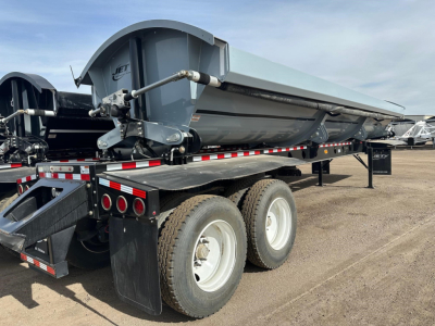 Jet trailer side dump showing hydraulic cylinder, dual axle with tires, and rear tarp; Jet logo on front hopper.