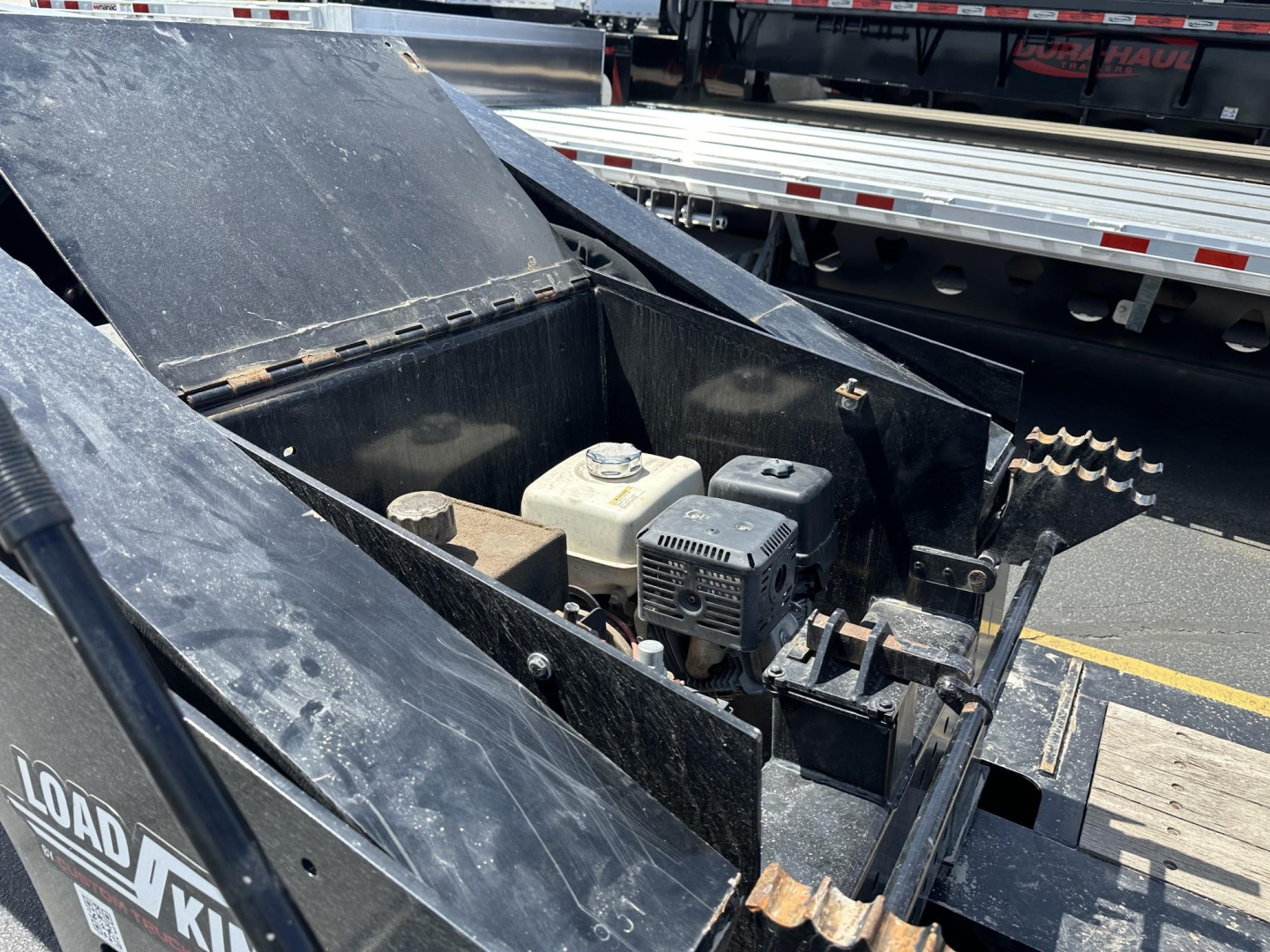 Trailer component view showing engine/generator unit and toolbox on a Load King RGn lowboy trailer (black metal, metallic components visible).