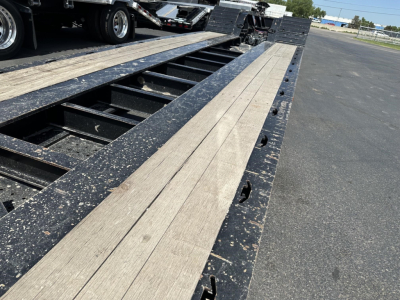 Load King RGn lowboy trailer deck and gooseneck area showing wooden planks and black steel frame with cutouts and fasteners.