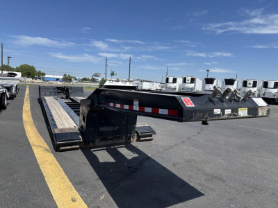 Load King lowboy trailer in-service showing gooseneck and long deck with loading ramps and safety reflectors.