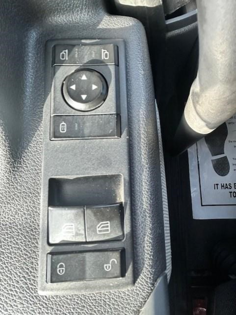 Truck interior window/ mirror controls panel with four switch buttons including mirror adjust arrows, window controls, and lock buttons.