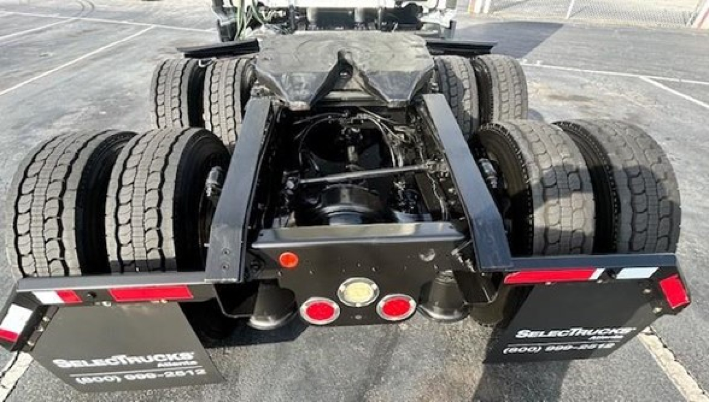 Freightliner Cascadia chassis rear showing fifth-wheel hitch and dual rear axles with multiple tires and mud flaps.