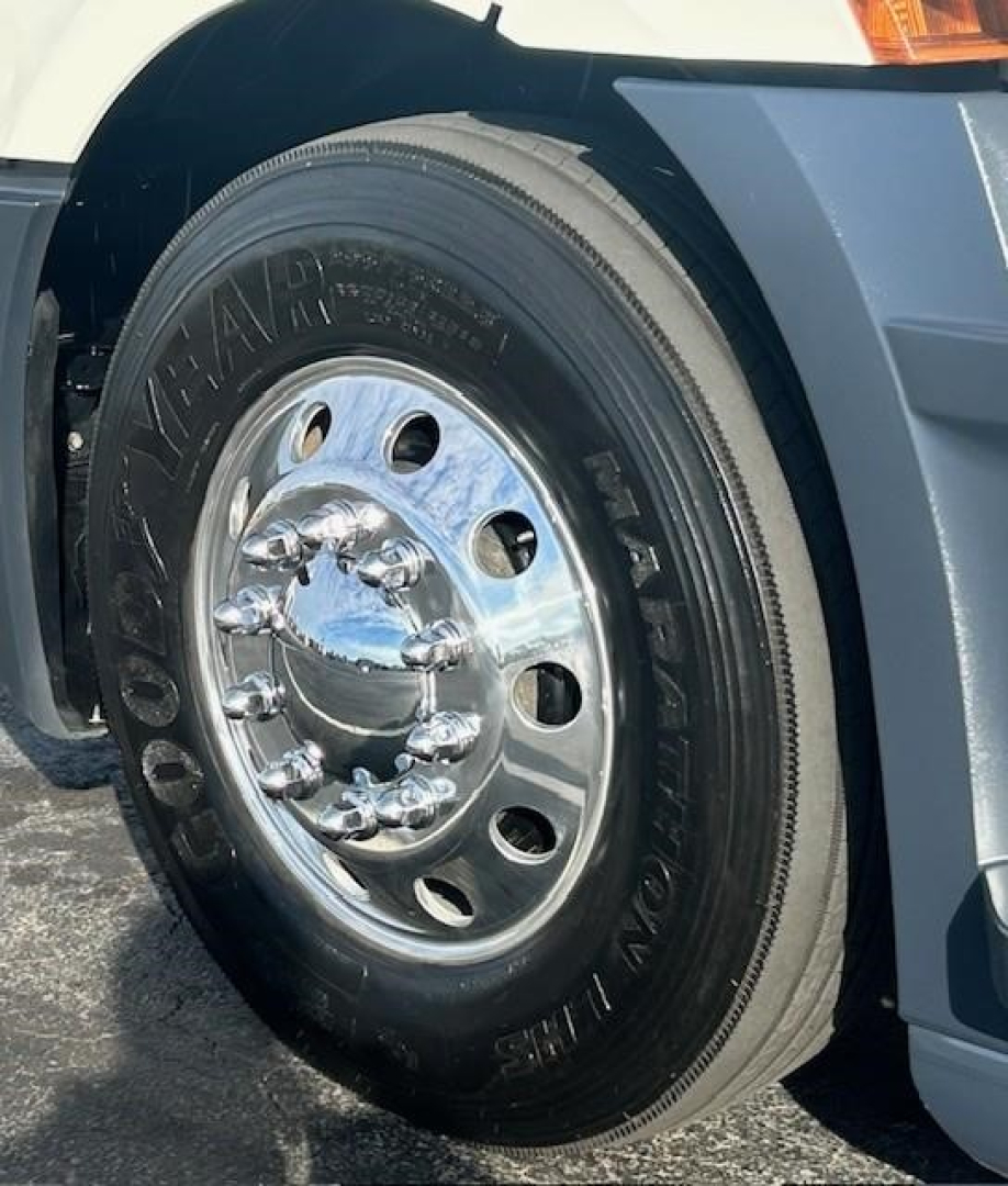 Wheel and front fender of a Freightliner Cascadia 126 truck showing Goodyear tire and chrome wheel with lug nuts.