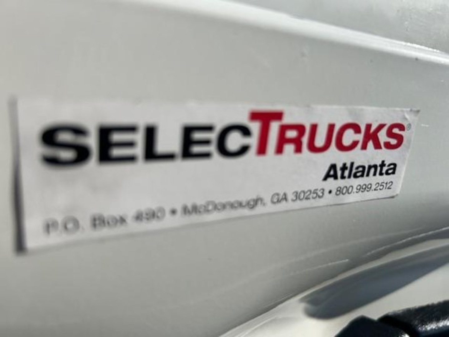 Sticker on Freightliner Cascadia showing SelectTrucks Atlanta, P.O. Box 490 McDonough GA, and a phone number.