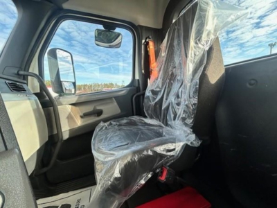 Interior front cab of a 2021 Freightliner Cascadia 126 day cab showing driver seat wrapped in plastic and steering wheel area.