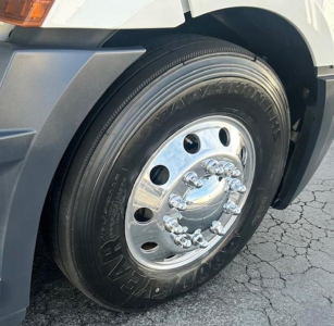 Truck wheel with Goodyear tire and chrome hubcap on Freightliner Cascadia 126 front wheel well.
