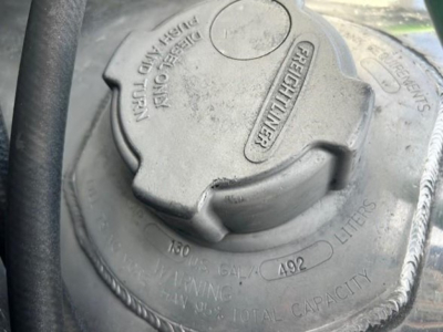 Truck fuel filler cap visible with embossed markings and 'LITERS' indicator in engine bay of a Freightliner Cascadia 126.