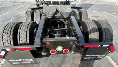 Freightliner Cascadia chassis rear showing fifth-wheel hitch and dual rear axles with multiple tires and mud flaps.