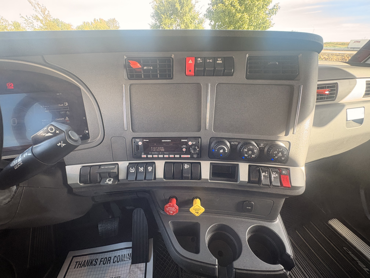Kenworth T680 dash and center console showing controls, vents, and knobs. Visible text includes warning symbols and various control labels.