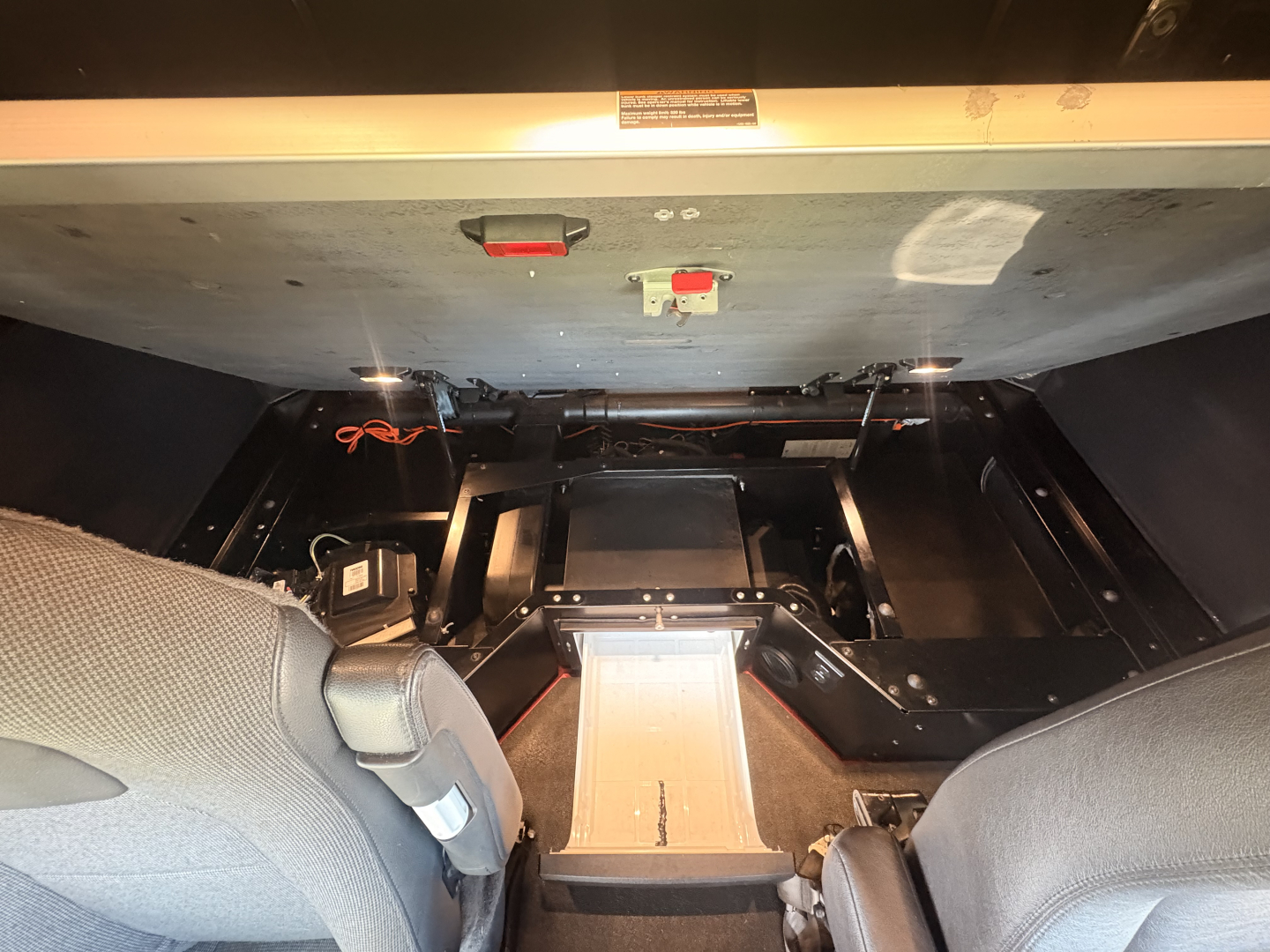 Interior view under Kenworth T680 cab showing exposed chassis components and a center platform; no legible text visible.