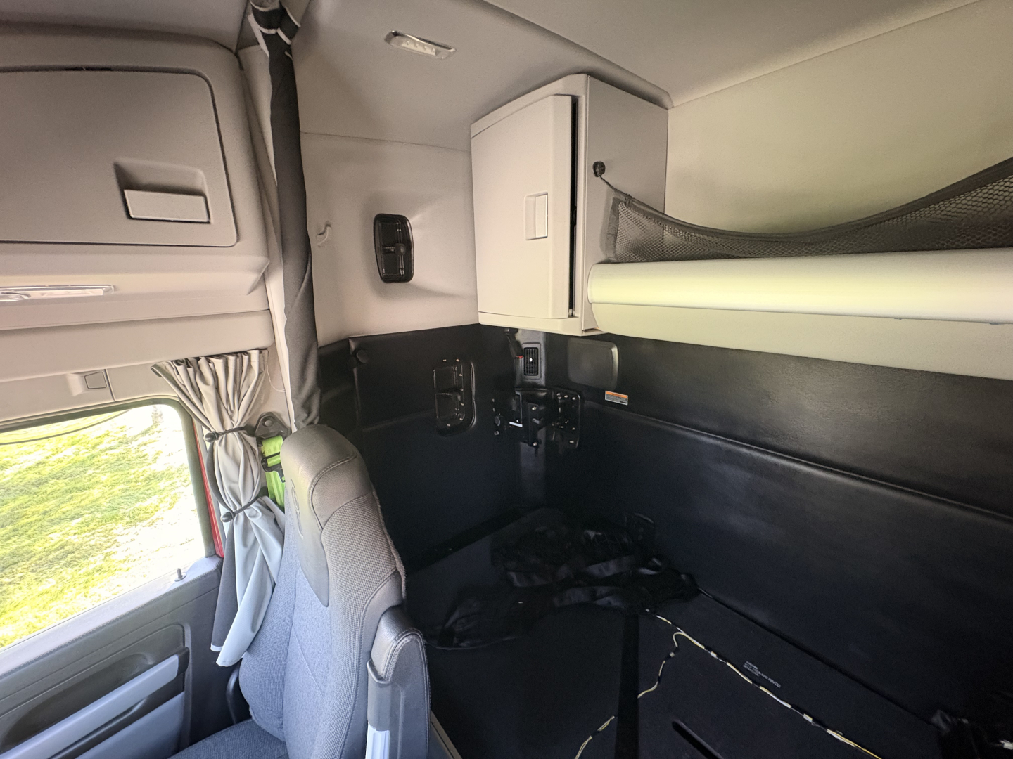 Kenworth T680 sleeper cab interior showing upper bunk, cabinets, and seating area with storage compartments.