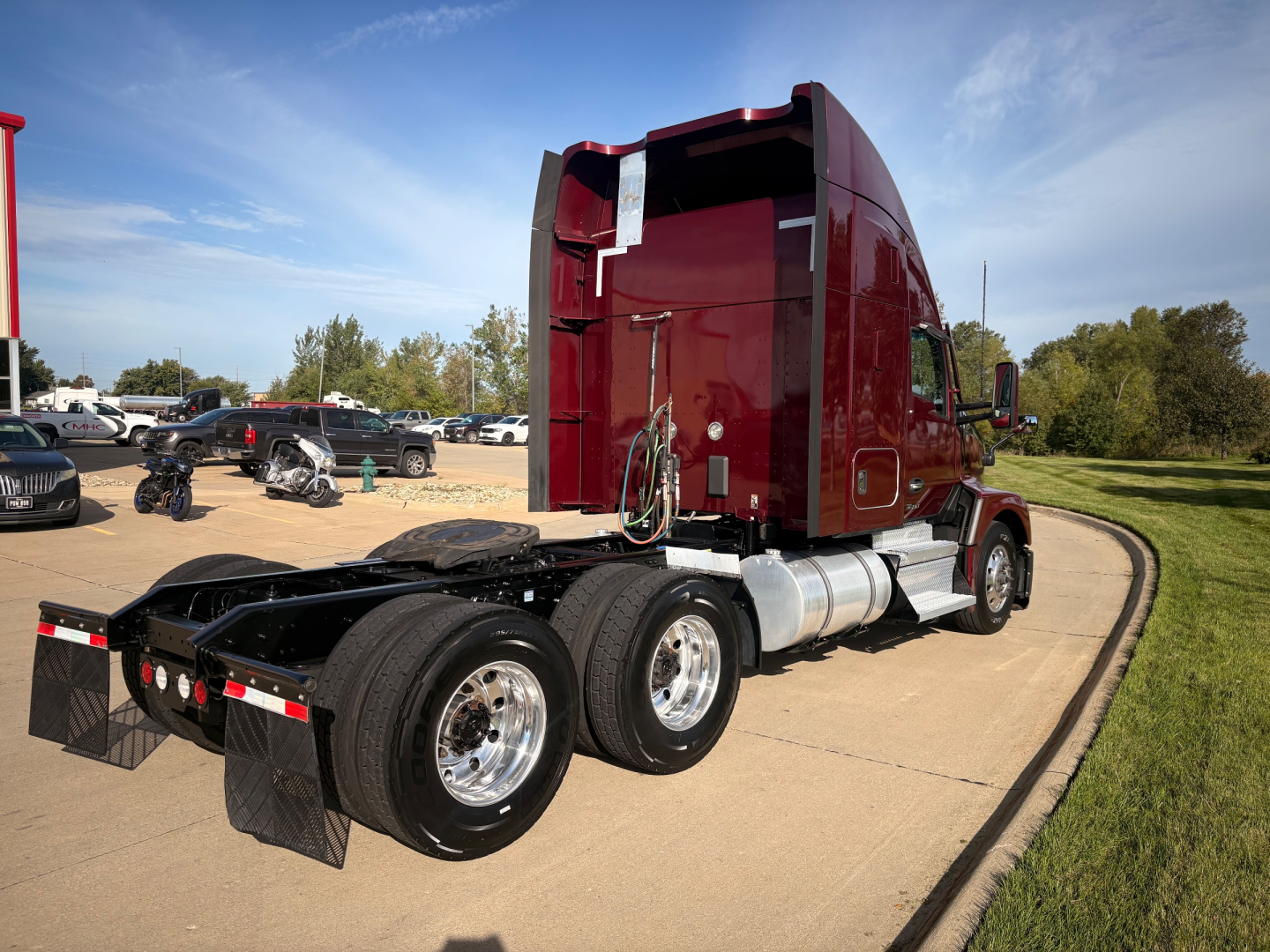 Kenworth T680 truck tractor rear/side view showing dual rear axles and sleeper cab with maroon paint.