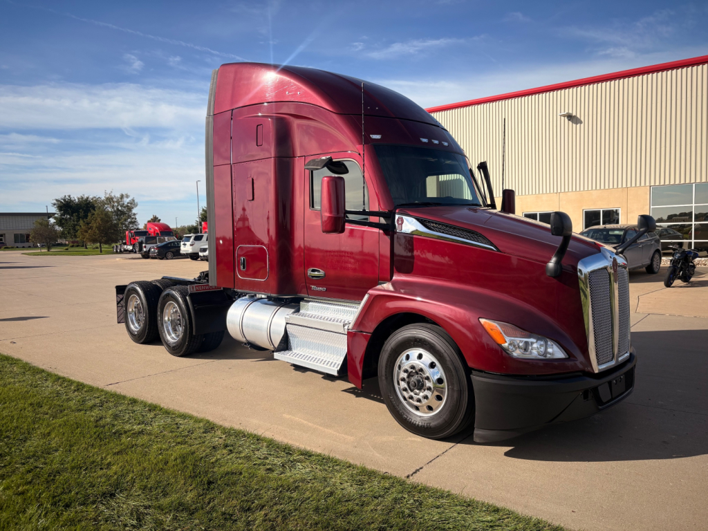 Kenworth T680 conventional sleeper tractor in red, side view with engine bay, fuel tanks, and wheels visible.
