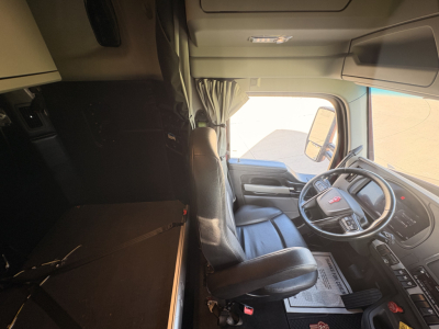 Kenworth T680 cab interior showing steering wheel, driver seat, and dashboard in-view.