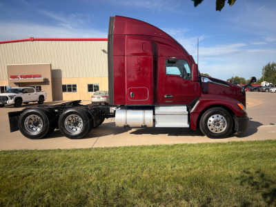 Kenworth T680 conventional sleeper tractor side view showing red cab, chrome fuel tanks, and dual rear axles.