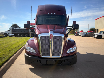 Kenworth T680 front view showing large chrome grille and headlights, red cab with black bumper and side mirrors.
