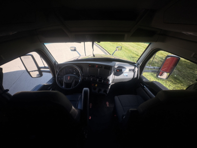 Kenworth T680 truck interior cabin dashboard view from passenger seat showing steering wheel gear shifter and instrument panel.