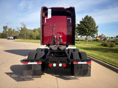 Kenworth T680 rear view showing dual rear axles, mud flaps, and platform with hoses and electrical connections.