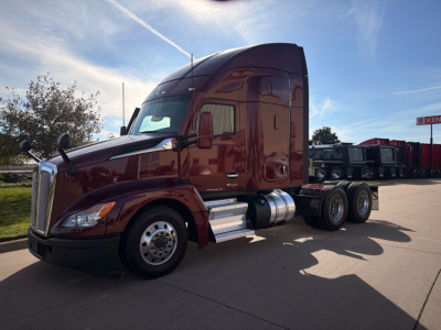 Kenworth T680 tractor-trailer in service showing side view with maroon cab and chrome fuel tanks.