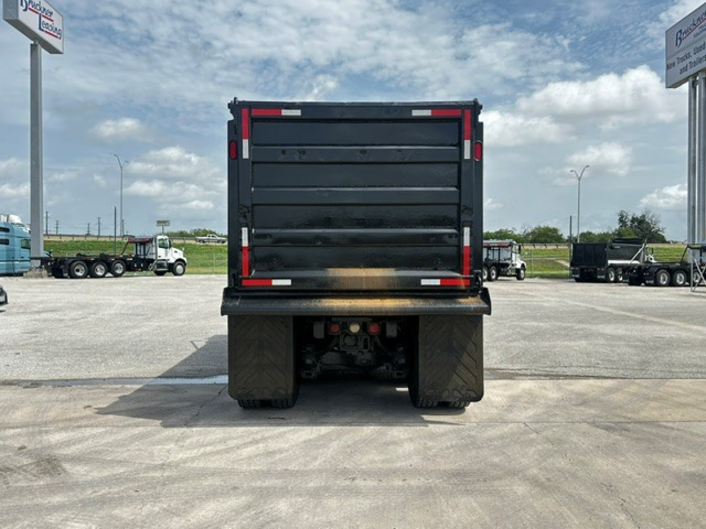 Dump truck bed rear view showing heavy-duty cargo area and taillights with black tailgate.