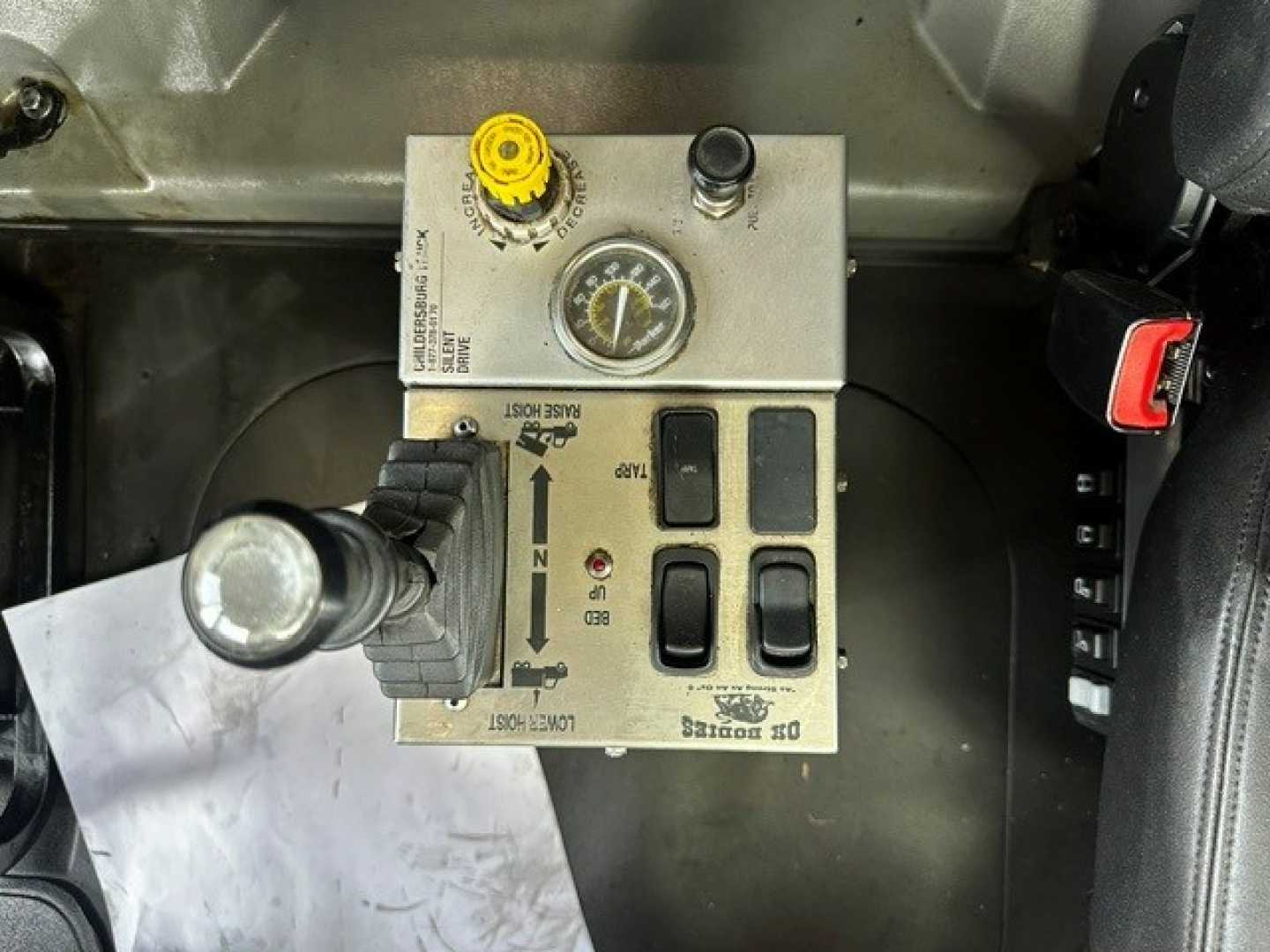 Panel of Mack GR64F cab showing control switches, gauge, yellow cap, and levers; labels visible around the control panel.