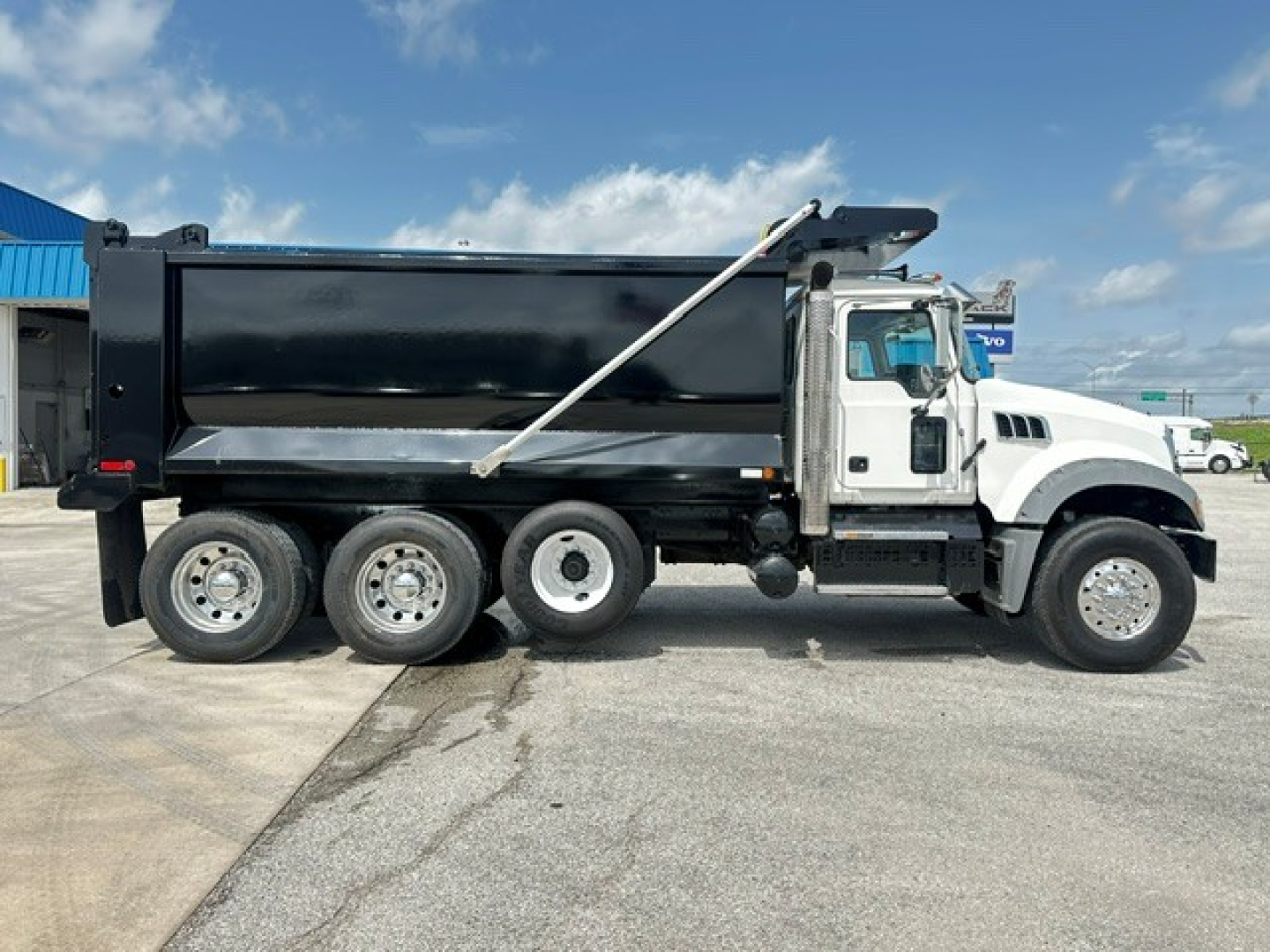 Dump truck side view showing Mack GR64F with black dump body and front white cab, six wheels visible, VIN 1M2GR4GC9LM019926 and stock B3430P.
