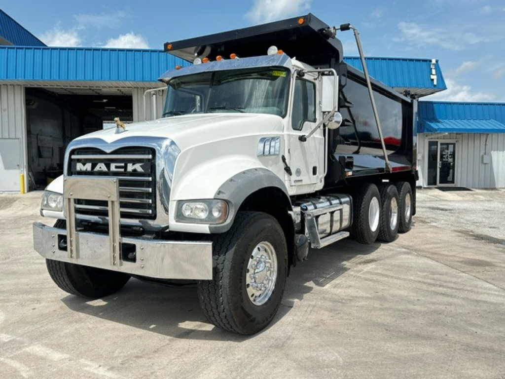 Mack GR64F dump truck in service showing front grille with MACK, bumper guard, dual rear wheels, and dumping bed.