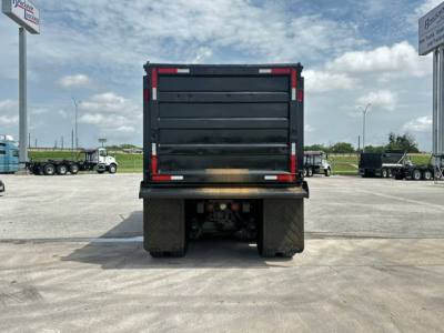 Dump truck bed rear view showing heavy-duty cargo area and taillights with black tailgate.